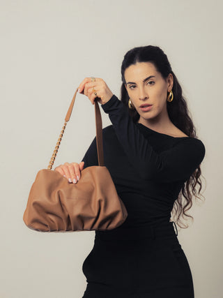 Modelo levantando el bolso Carmen Camel en estudio. Valentina Rivera Madrid.