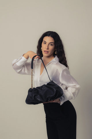 Modelo levantando el bolso Carmen negro en estudio en mano depie. Valentina Rivera Madrid.