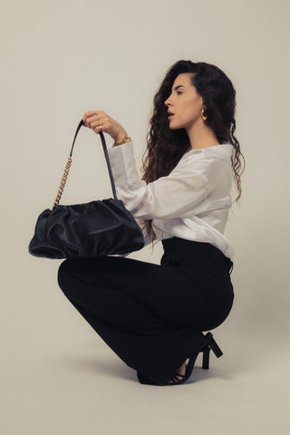 Modelo levantando el bolso Carmen negro en estudio. Valentina Rivera Madrid.