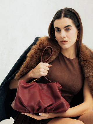 Modelo sentada con el bolso Carmen burdeos en estudio. Valentina Rivera Madrid.