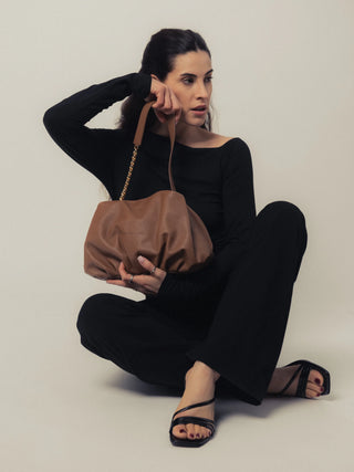 Modelo sentada con el bolso Carmen camel en estudio. Valentina Rivera Madrid.