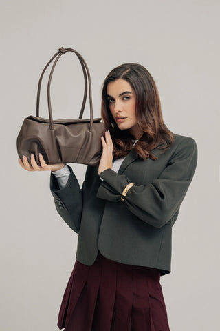 Modelo levantando el bolso Leonor Chocolate en estudios. Valentina Rivera Madrid.